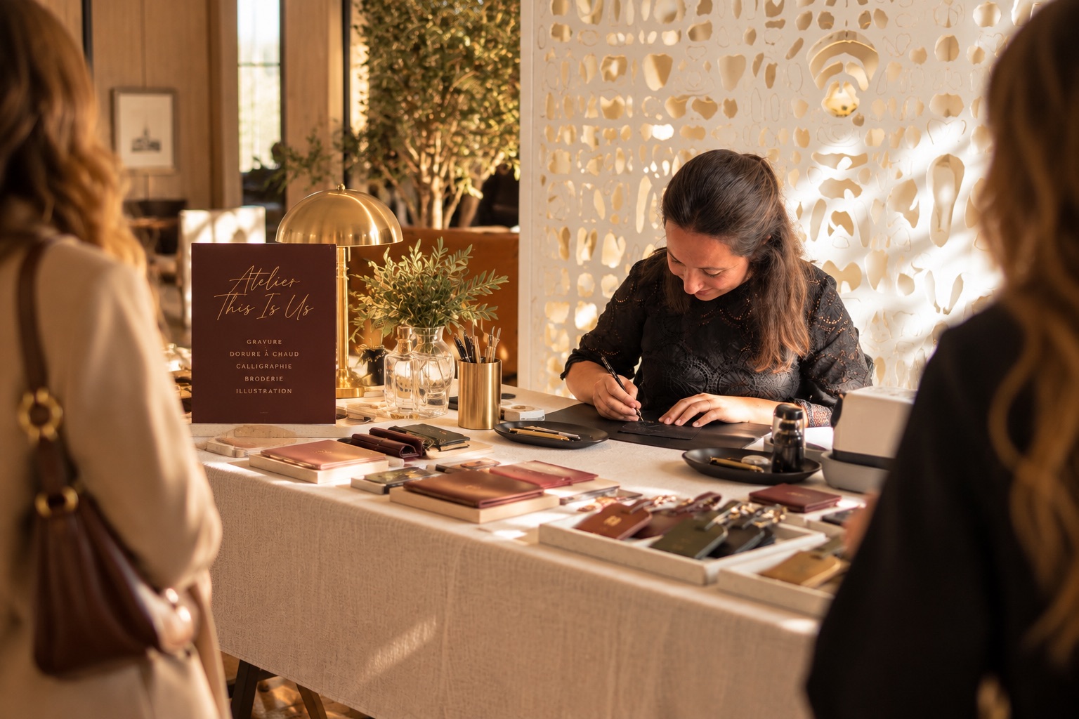 Laure Vidal personnalise en direct des étiquettes à bagage et des étuis en cuir devant des invités, sur le stand de l'Atelier This Is Us